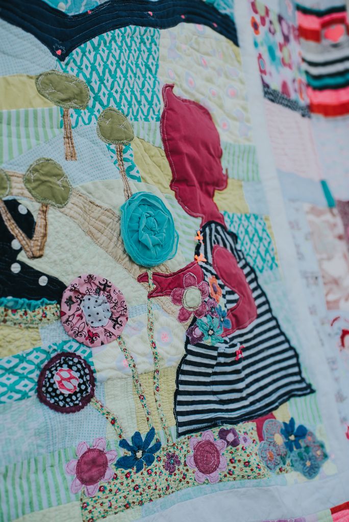 Pink silhouette of a little girl picking a flower on a memory quilt made from that girls' clothing.