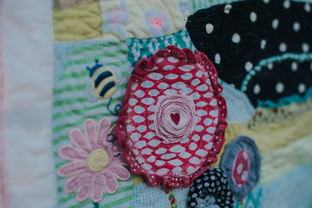 Flower made from baby clothes and used as an applique in a memory quilt.