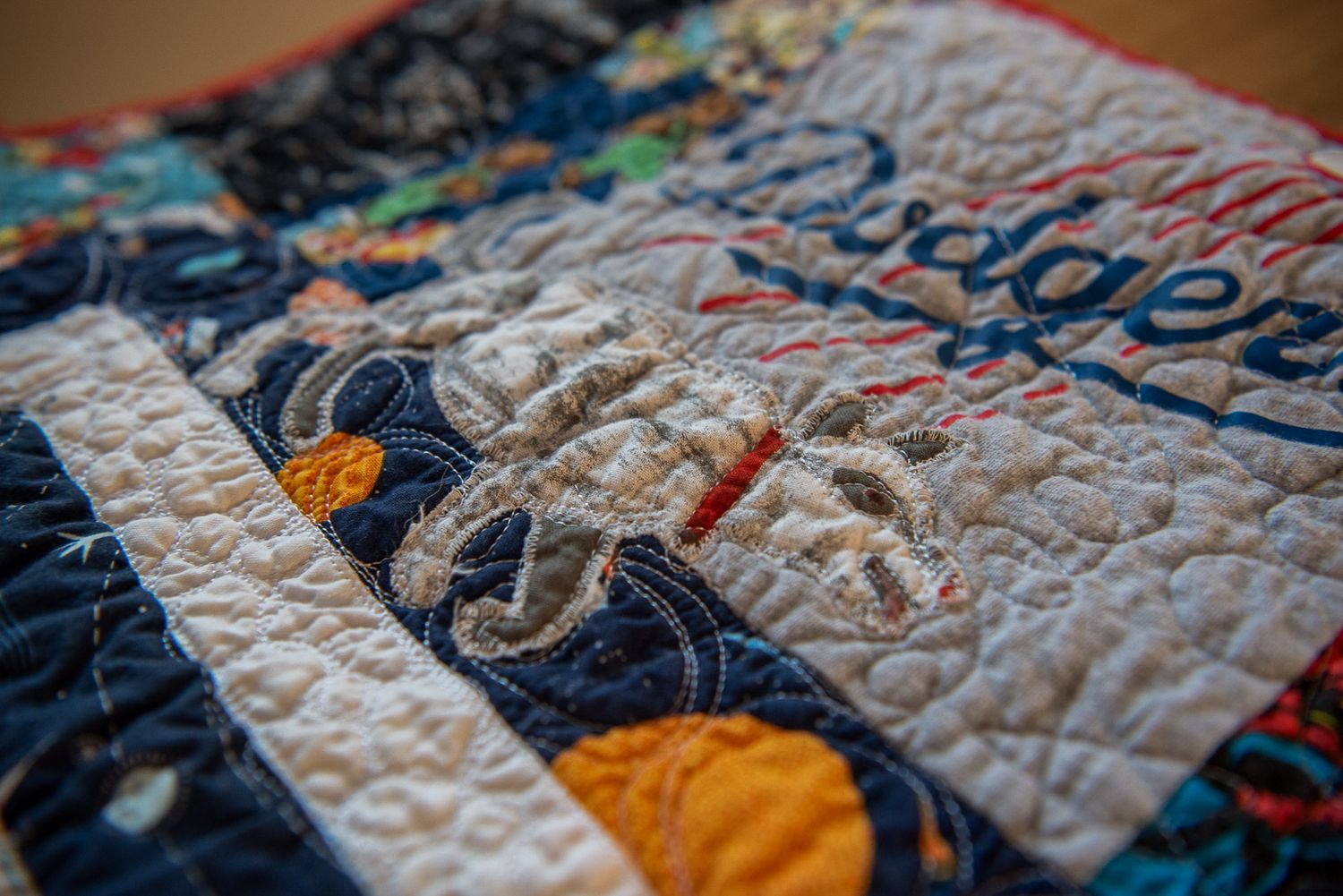 Detailed image of an applique made from fabric of Eric Carle's drawing of a dog.