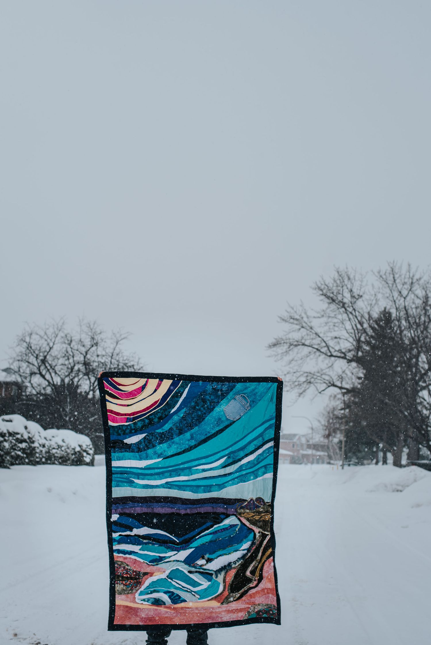Susseration of the soul memorial quilt held up in the street on a snowy day.
