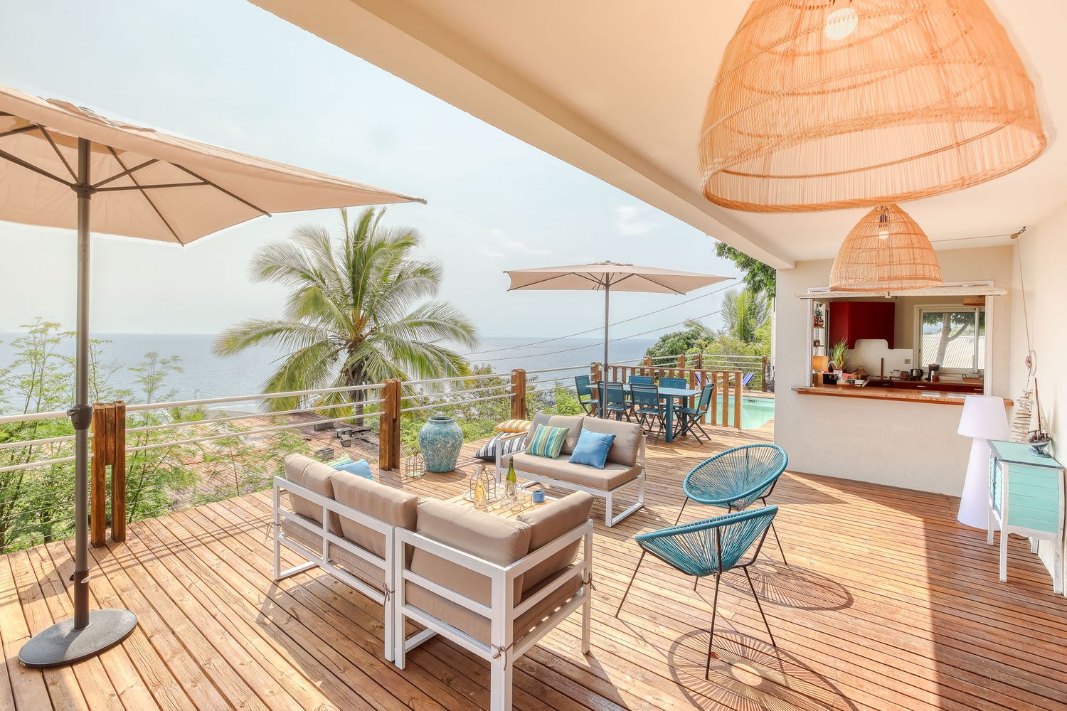 Oceanfront deck with comfortable seating and umbrellas overlooking tropical coastline.