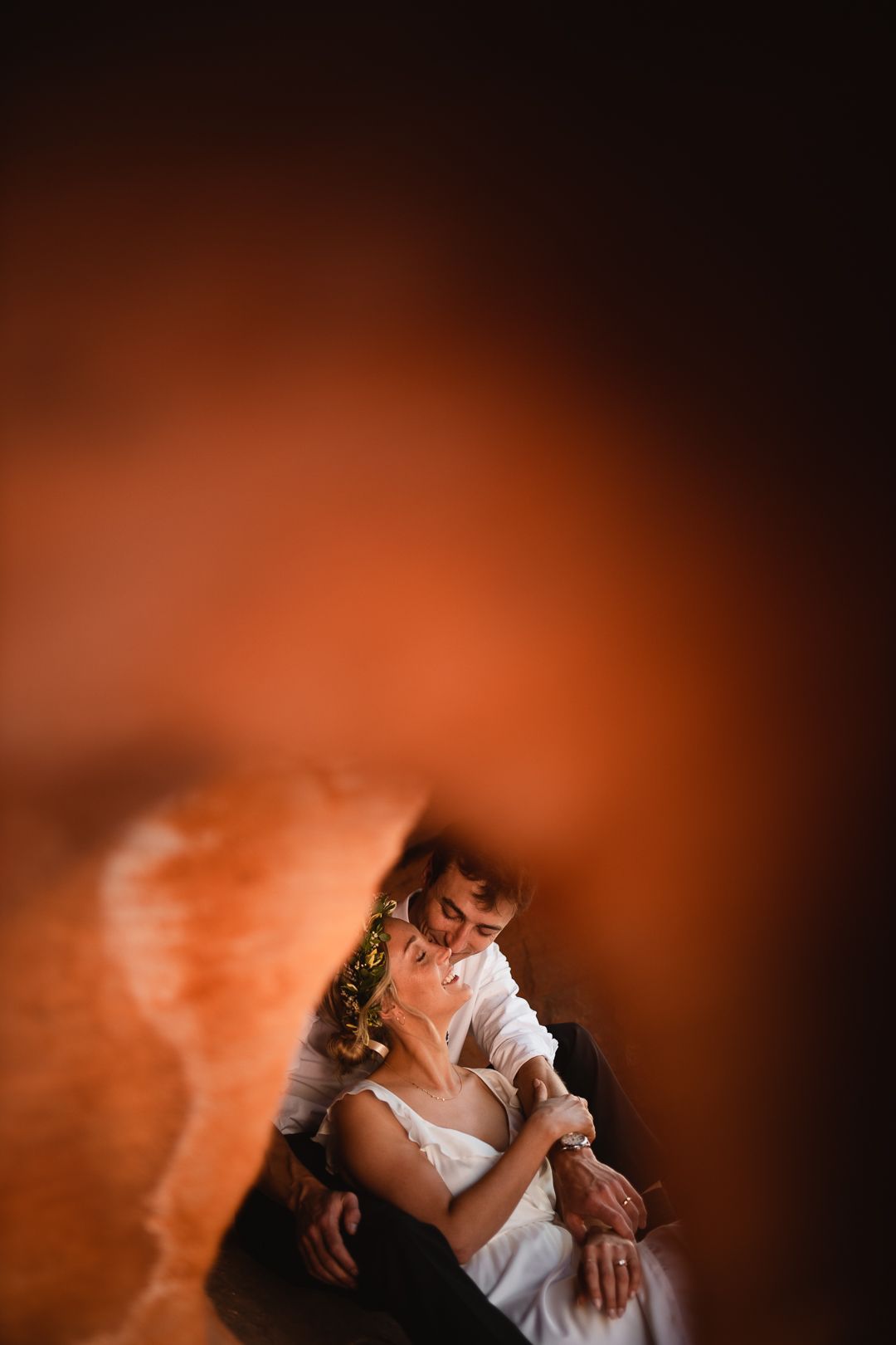 Couple under a red rock arch on their wedding day.  Adventure elopement wedding.