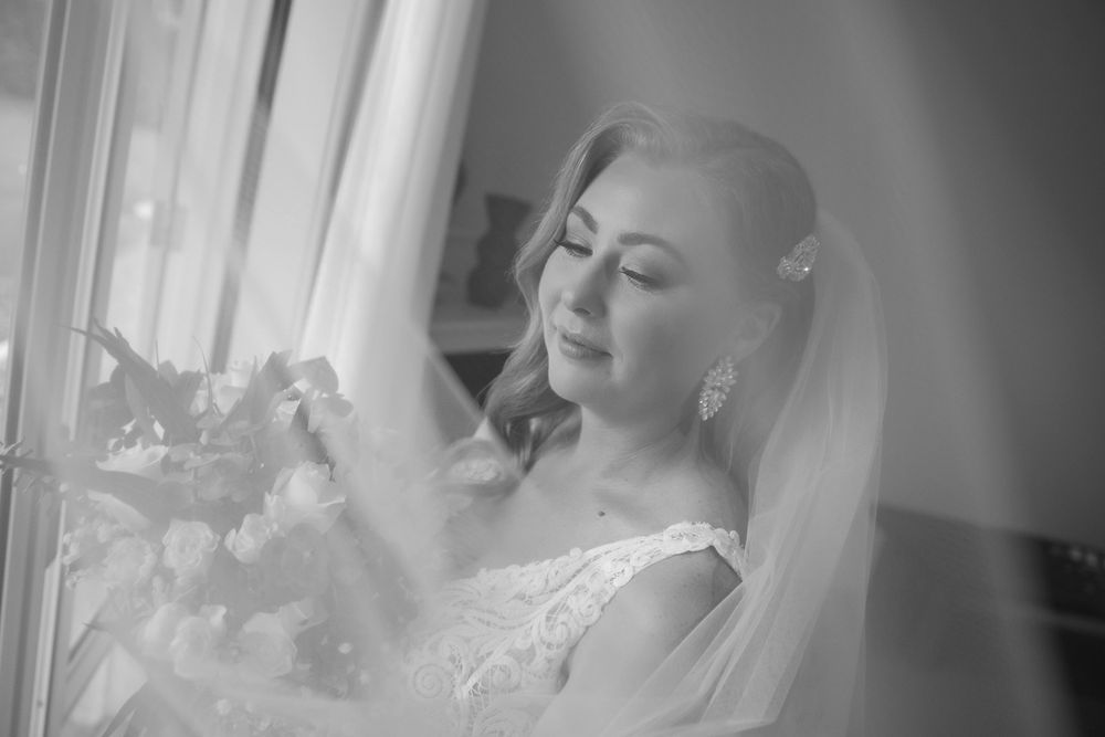 Bride in her wedding dress looking through her veil holding her flowers before her ceremony at Lancemmore in Milawa