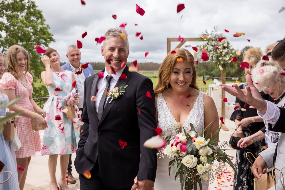 Bride and Groom with their guests during their ceremony at Lancemore Milawa, with rose pedals being thrown.