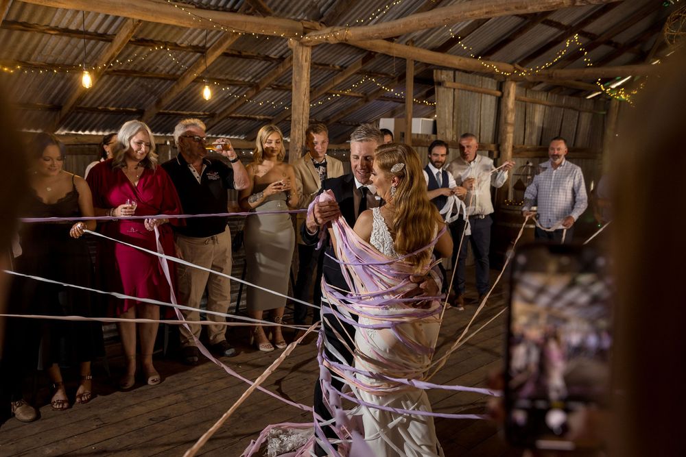 The Bride and Groom enter their reception at the Milawa Providore as their guests wrap them in coloured streamers.