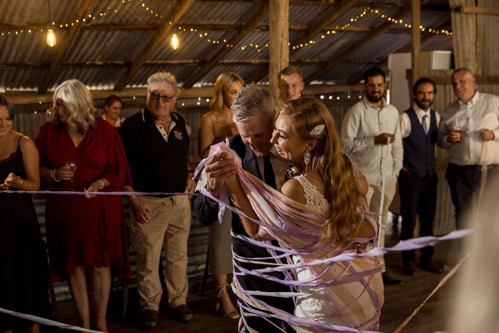 The Bride and Groom enter their reception at the Milawa Providore as their guests wrap them in coloured streamers.