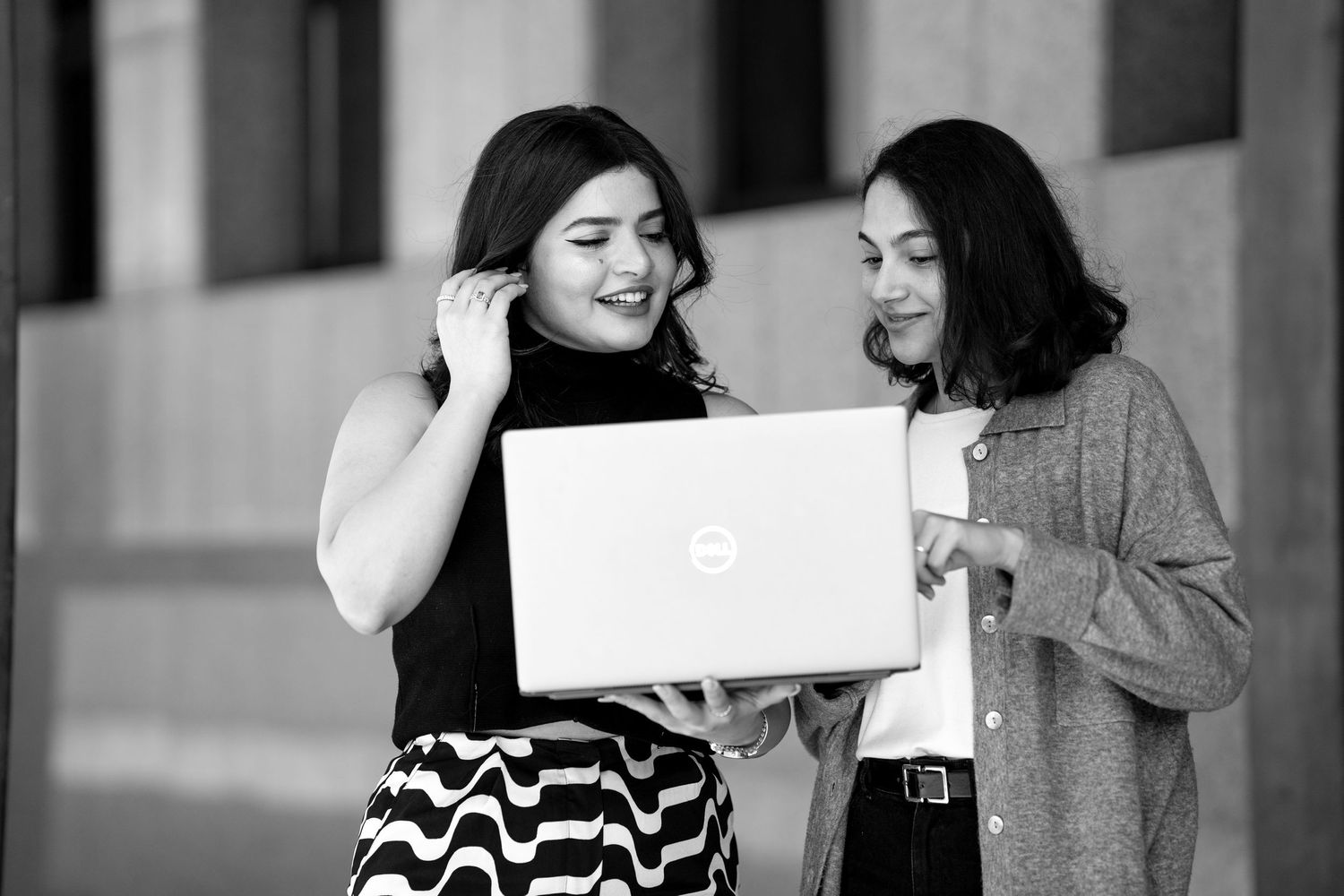 Two women sharing a joyful moment while looking at a laptop computer.