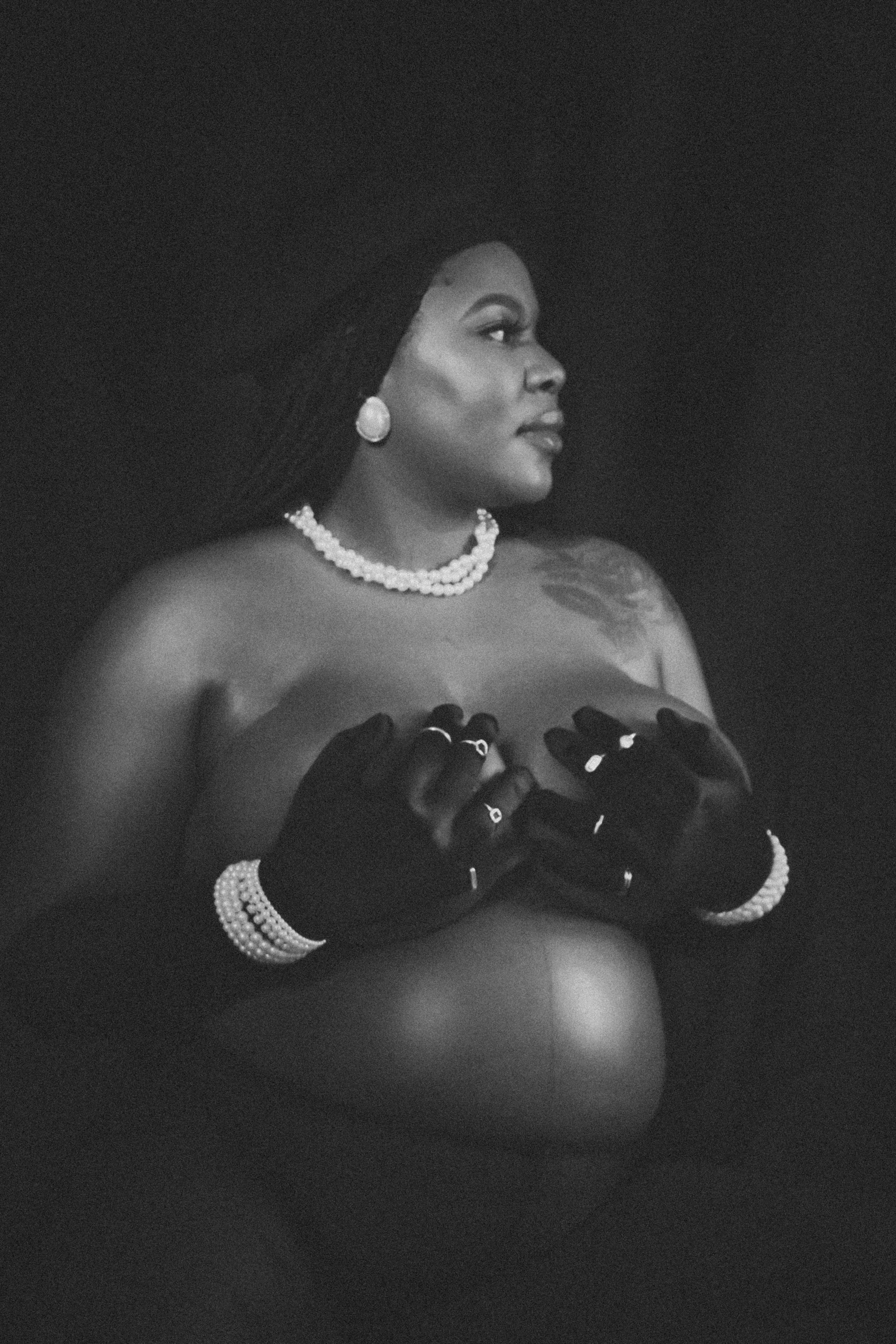 Dramatic monochrome maternity photo with pearl necklace and long black gloves creating elegant contrast.