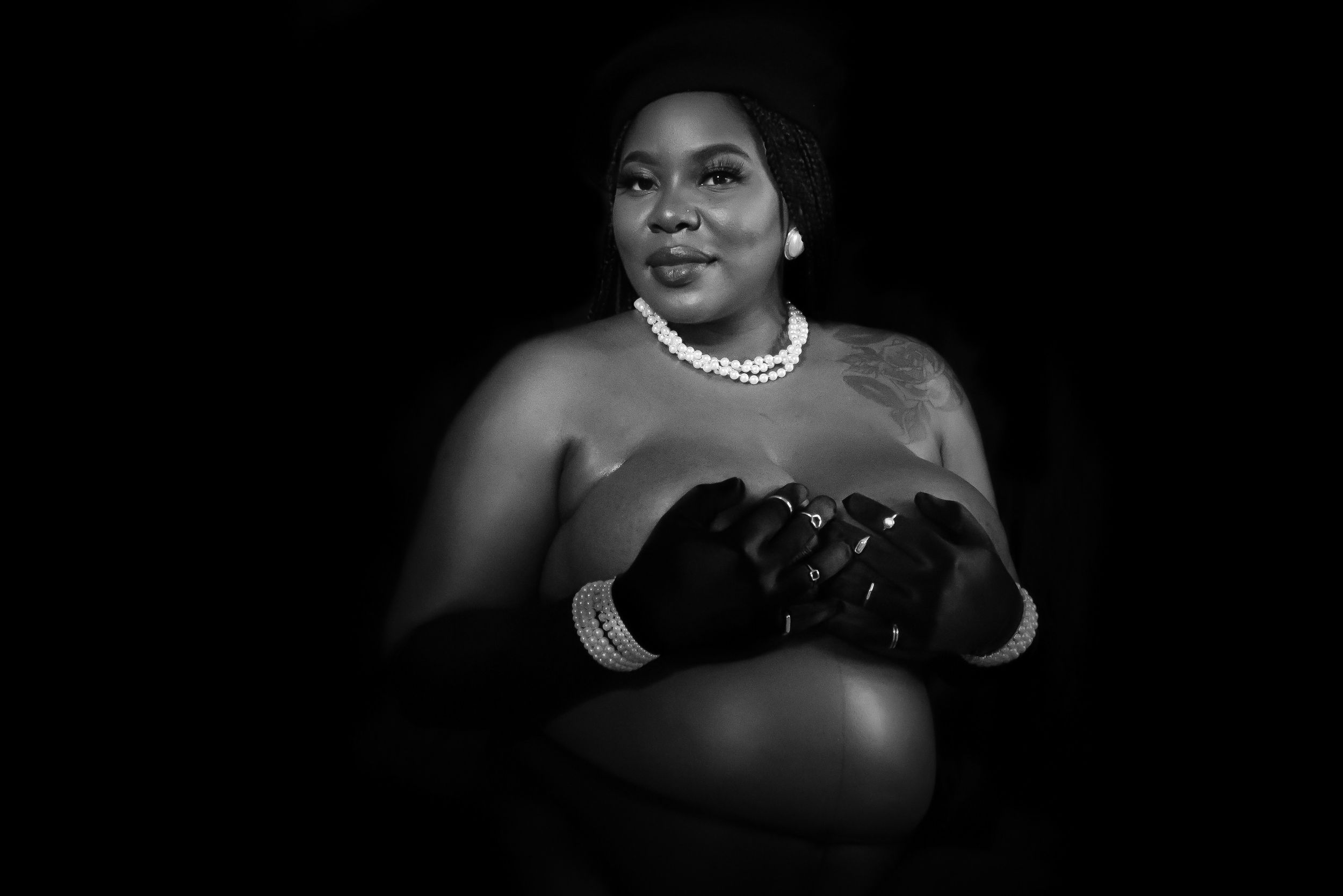 Dramatic black and white maternity portrait featuring a pearl necklace and black strapless dress.