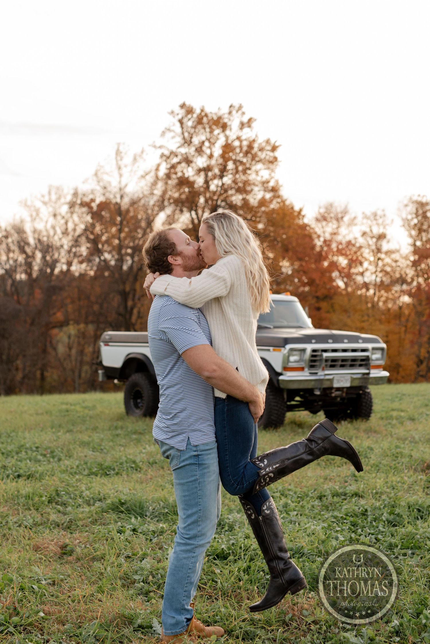 Romantic autumn photoshoot in a field with a vintage lifted Ford truck visible in background.