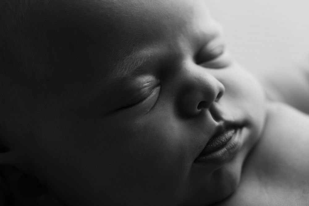 Black and white macro shot of newborn baby girl's face.