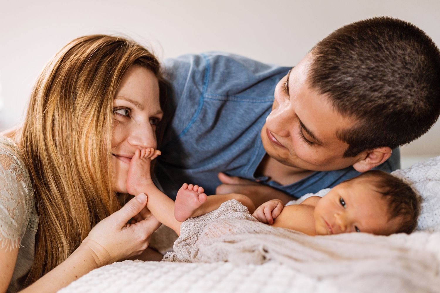 dad looking at mom while mom is kissing newborn feet for pose photo taken by heart and root photography