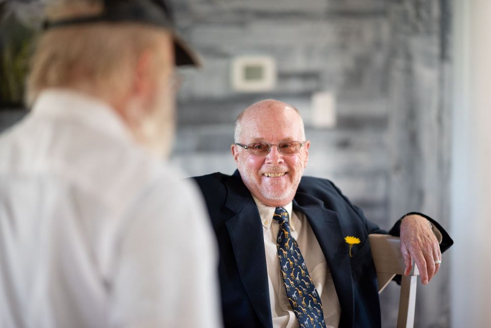 A man in a suit and tie smiles during what appears to be a business or social gathering.