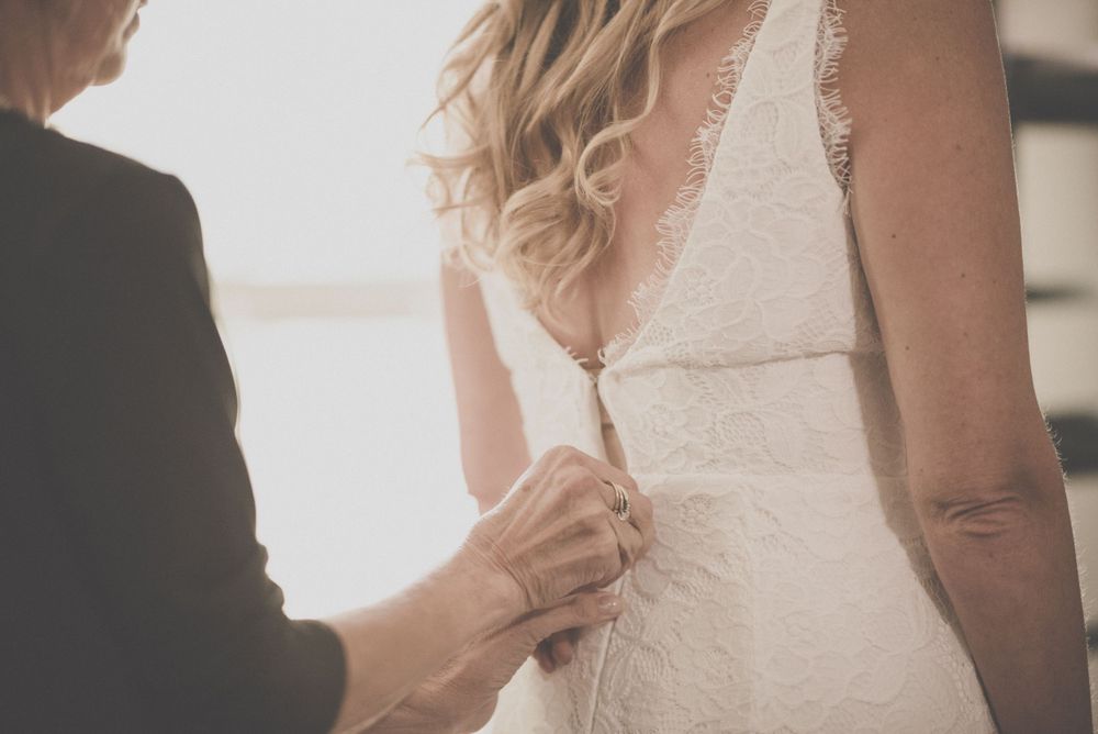 Close-up shot of someone adjusting the back of a white lace wedding dress.