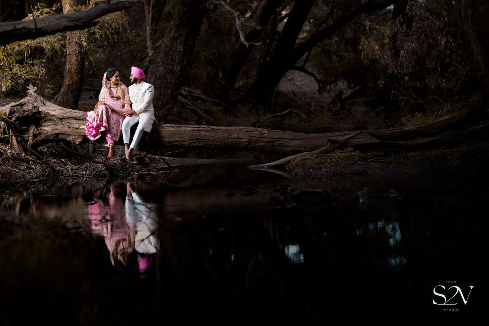 A romantic lakeside photo with pink dress beautifully reflecting in the still dark water at dusk.