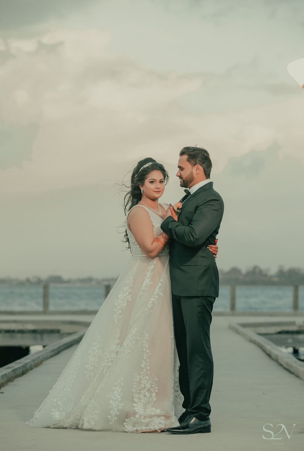 A romantic dock photoshoot with elegant white wedding dress against a moody overcast sky.