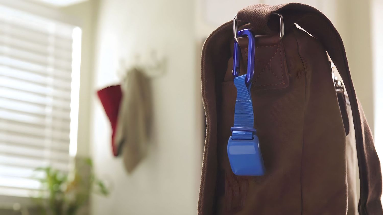 Blue plastic clip hanging on dark garment in home setting.
