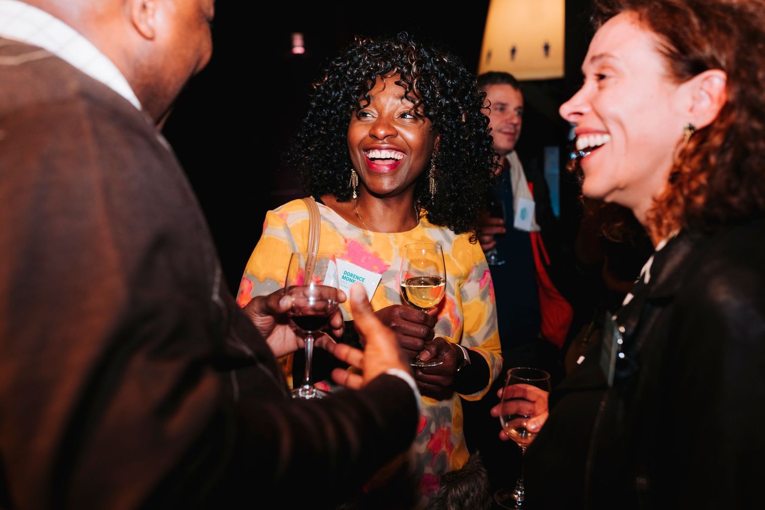 Evening party scene showing joyful interaction between guests holding wine glasses.