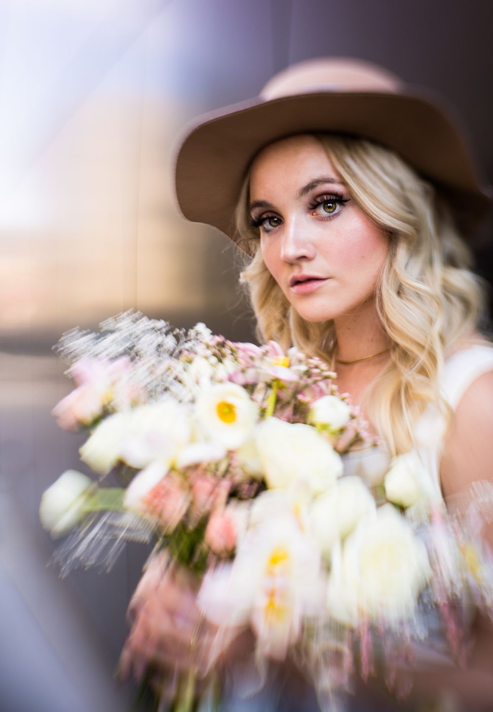Dreamy portrait with soft focus bouquet of white flowers and elegant hat.