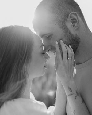 Intimate black and white close-up of couple sharing tender moment outdoors.