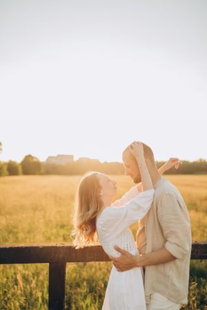 Couple in white clothing dancing and embracing in sun-drenched meadow.