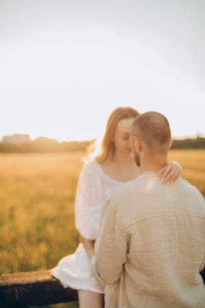 Soft focus romantic moment between couple beside wooden fence at sunset.