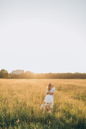 A romantic golden hour photoshoot in a sunlit meadow with tall grass and a dreamy atmosphere.
