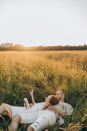 Two people relaxing in a sun-drenched summer field during golden hour.