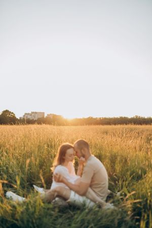 A tender moment shared in a golden wheat field during sunset.