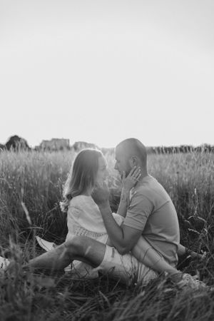 A black and white intimate portrait captured in tall grass during sunset.