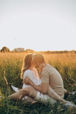 Romantic couple sharing an intimate moment in a golden wheat field at sunset.
