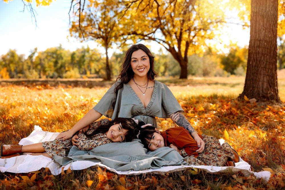 A cozy autumn picnic scene with blankets and wine set against golden sunlit trees in a park.