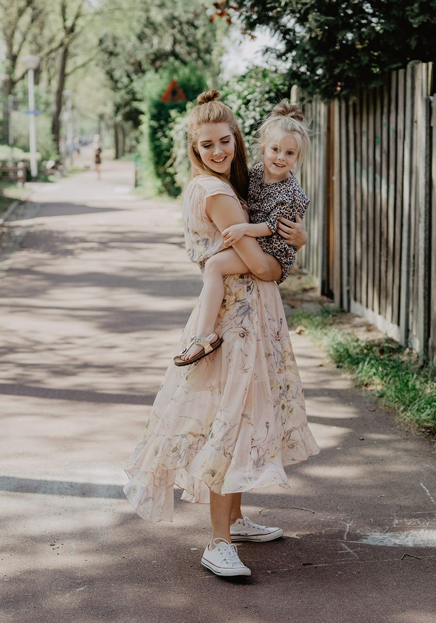 Mother and child sharing joyful moment on tree-lined pathway in summer.