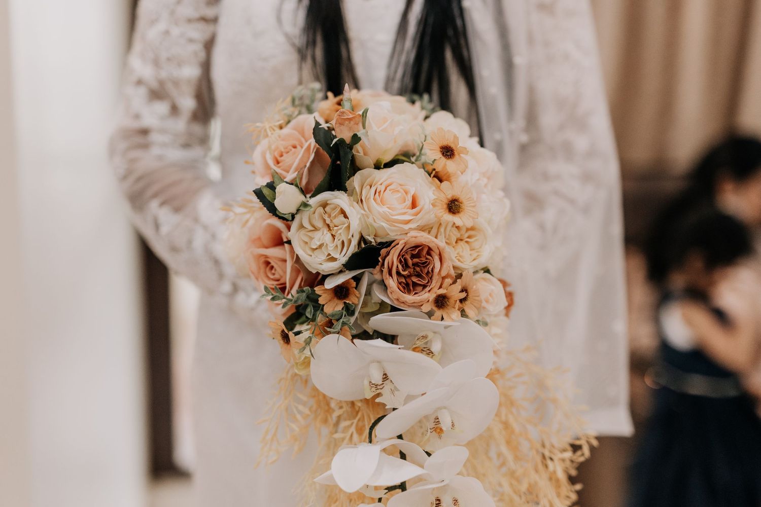 A delicate bouquet of peach and cream roses with flowing ribbons.