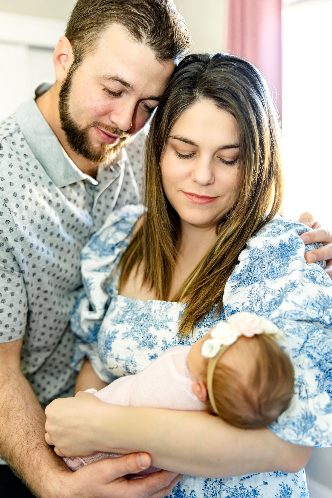 Parents stand holding their new baby girl and smile down at her during newborn photos in Colorado Springs.
