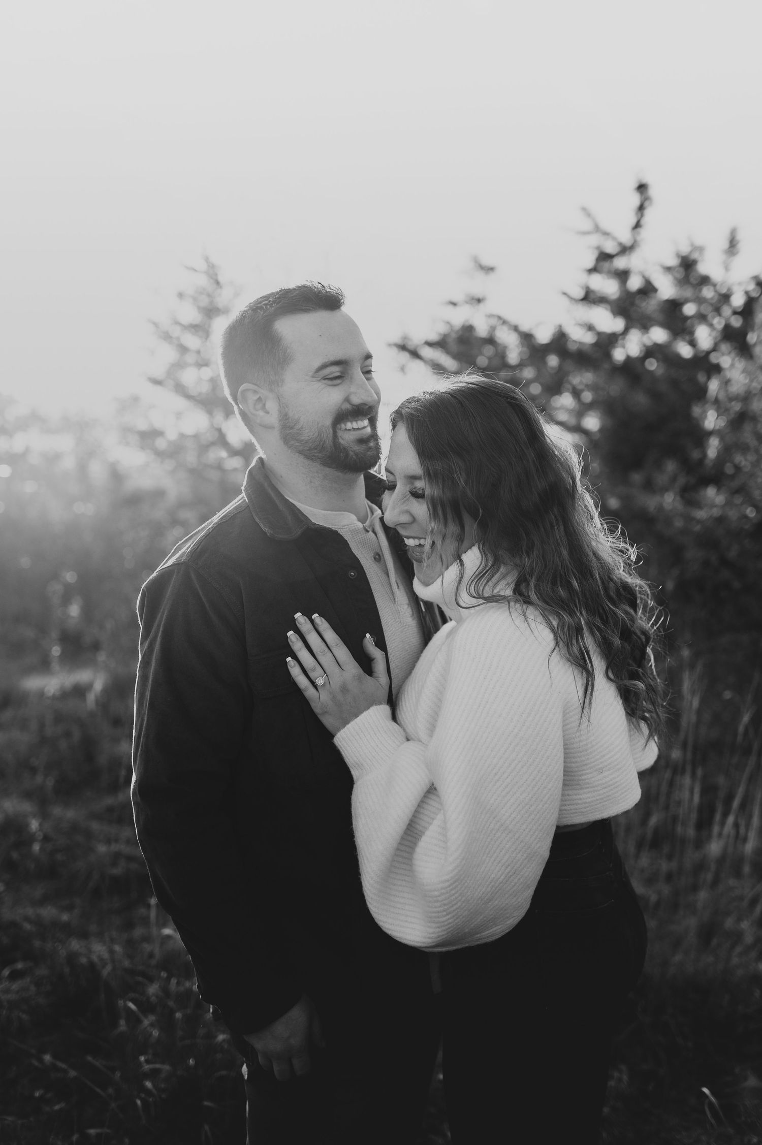 A romantic black and white portrait of a couple sharing intimate moments outdoors.