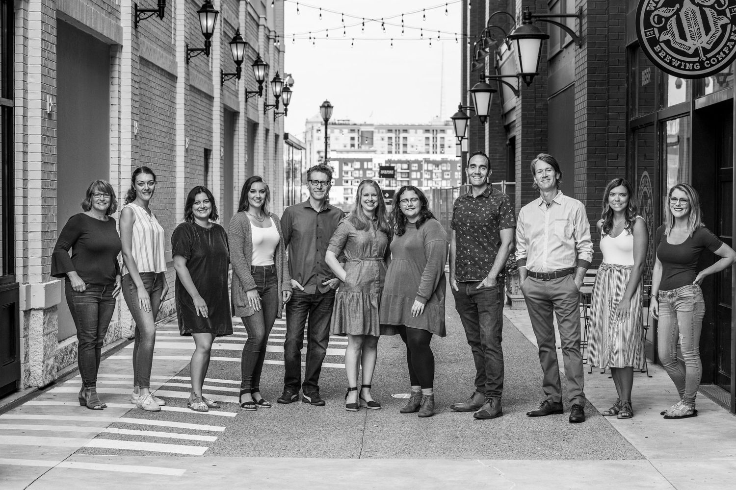 Group of people posing together on urban sidewalk in black and white photography.