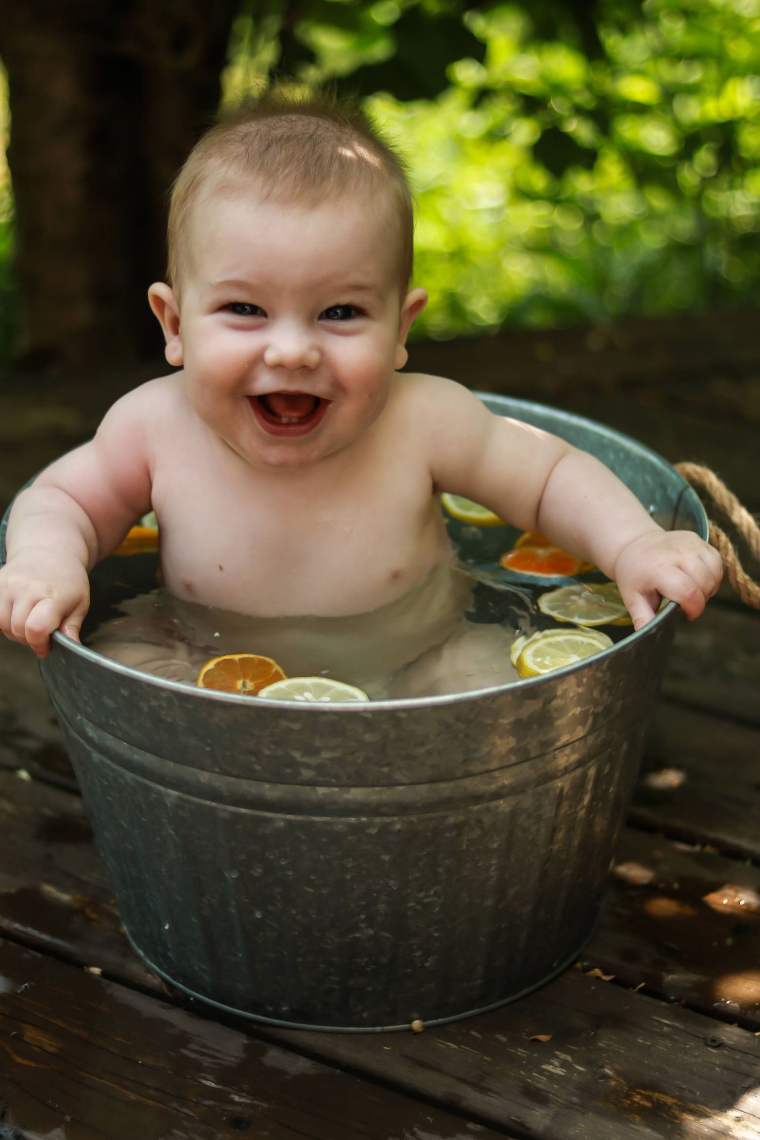 A Happy baby in a bucket of water with fruit