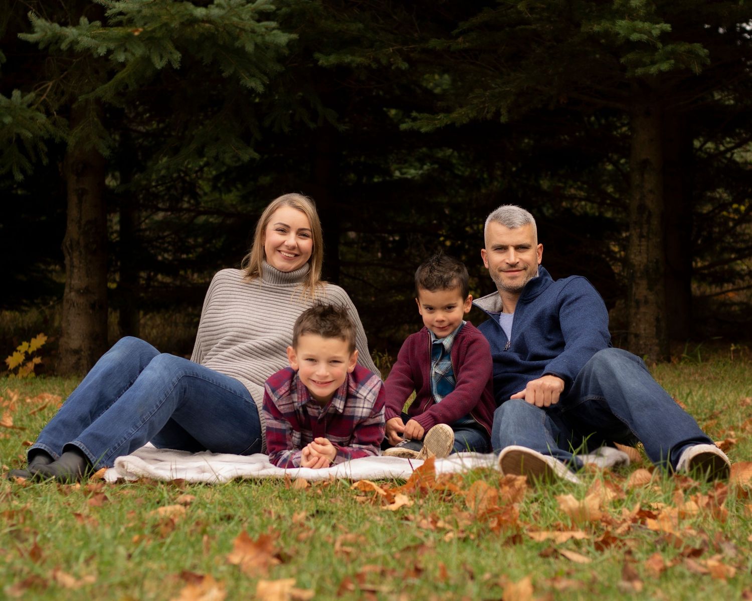A family of 4 cuddling on a blanket in the fall