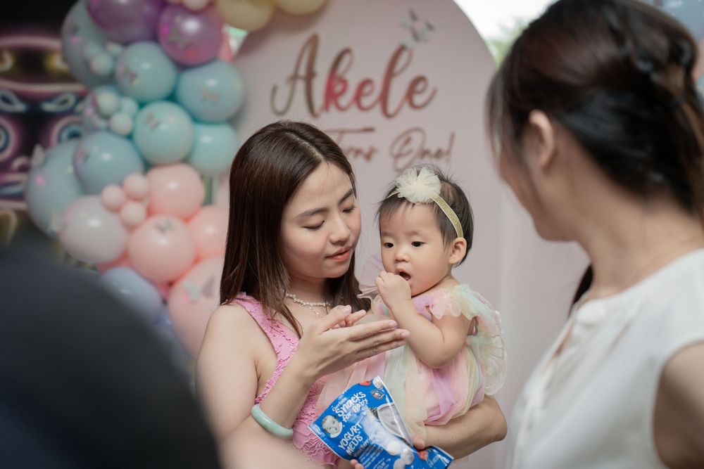 Birthday celebration with pastel balloon decorations and guests gathered around at a party.