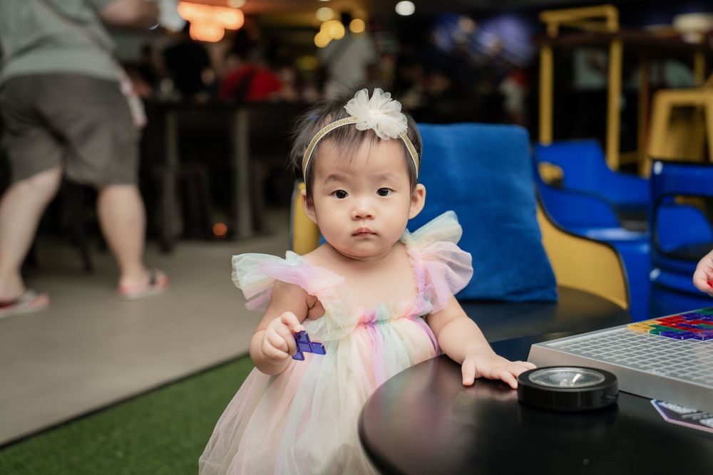 A toddler in a pink tulle dress exploring party decorations.