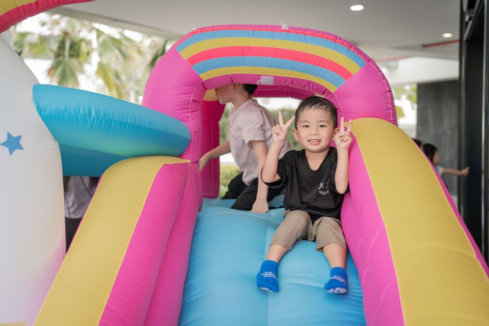 Children playing and sliding down a vibrant rainbow-colored inflatable bounce house.