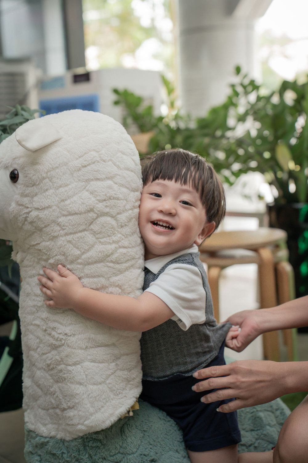 A child hugs a large plush stuffed animal while smiling joyfully.