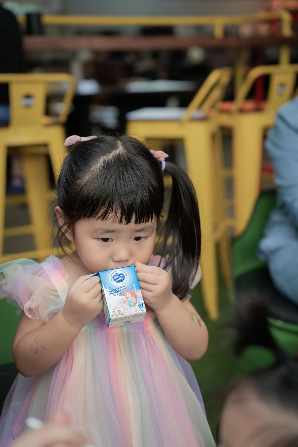 Young child in tulle dress enjoying a drink at party.