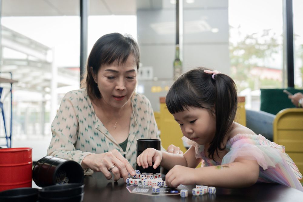 Adult and child working together on a craft project at a table.