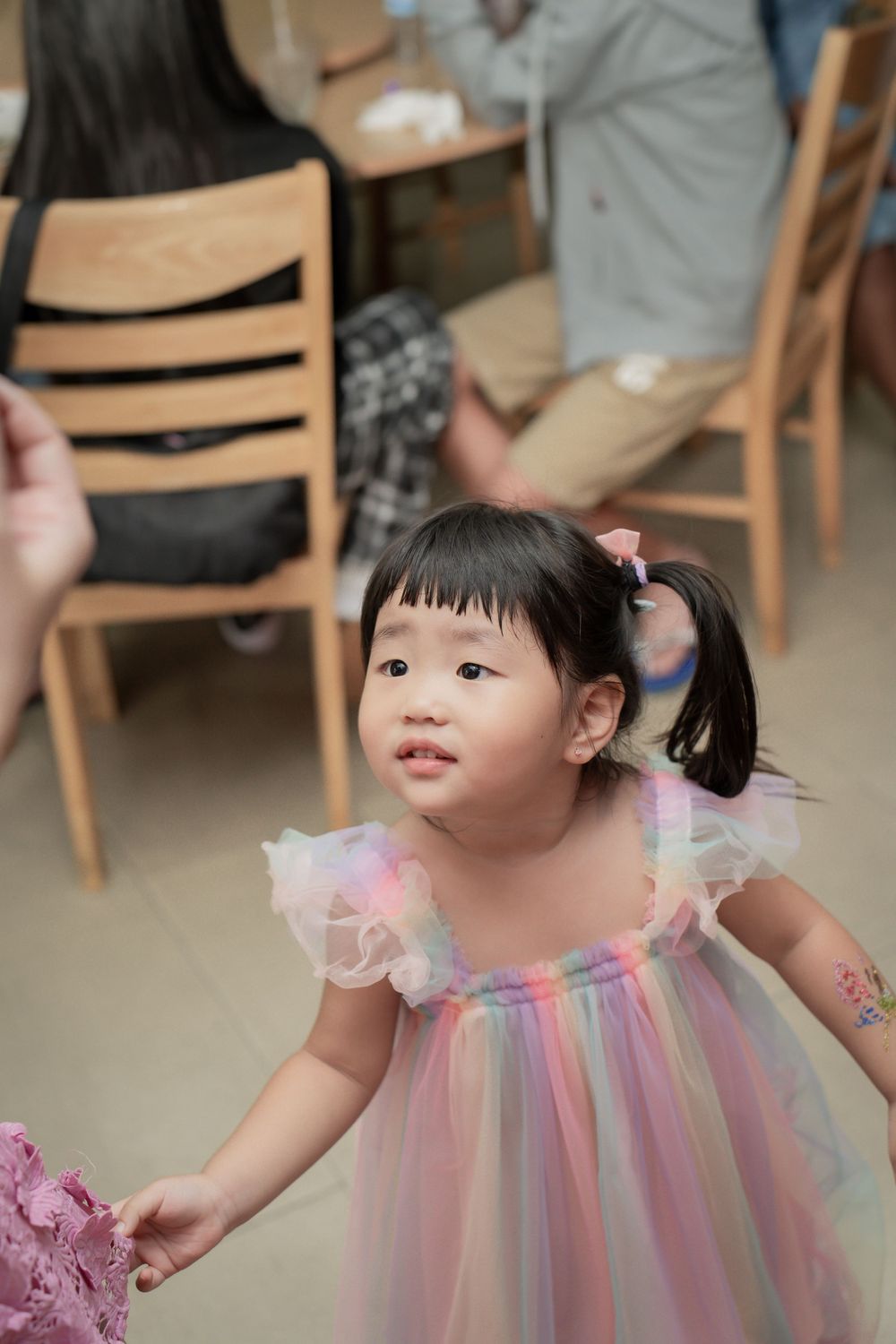A young child wearing a pastel rainbow tulle dress at a party celebration.
