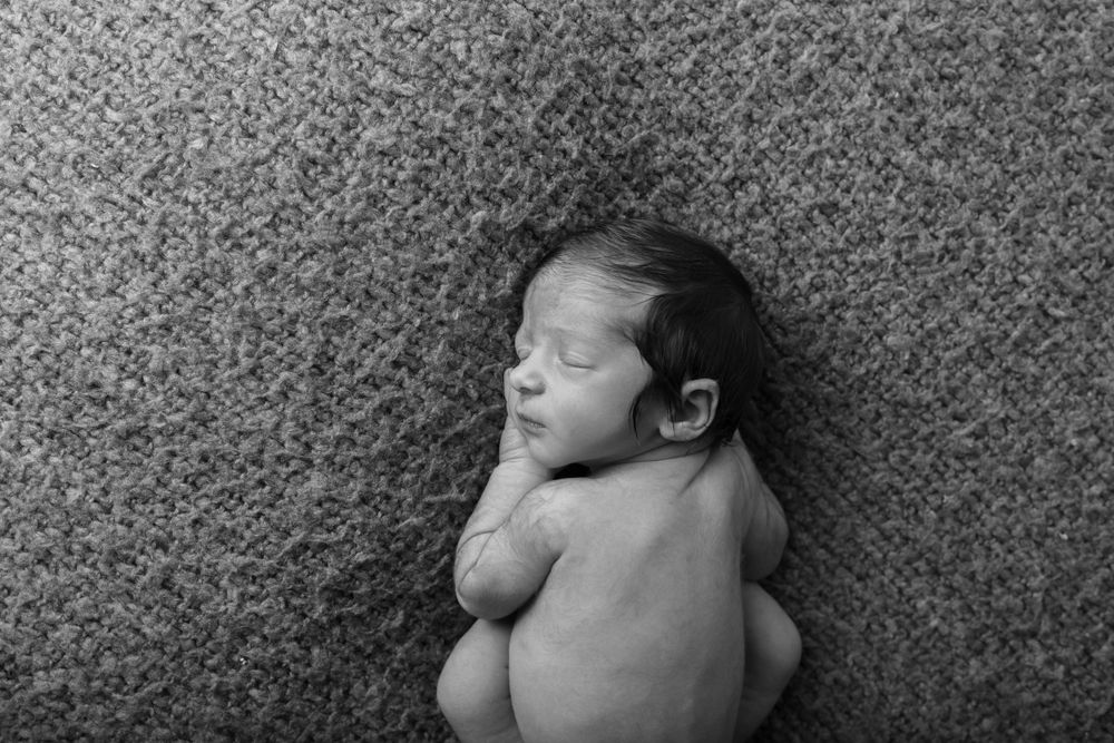 Black and white artistic portrait of a sleeping newborn on textured background.