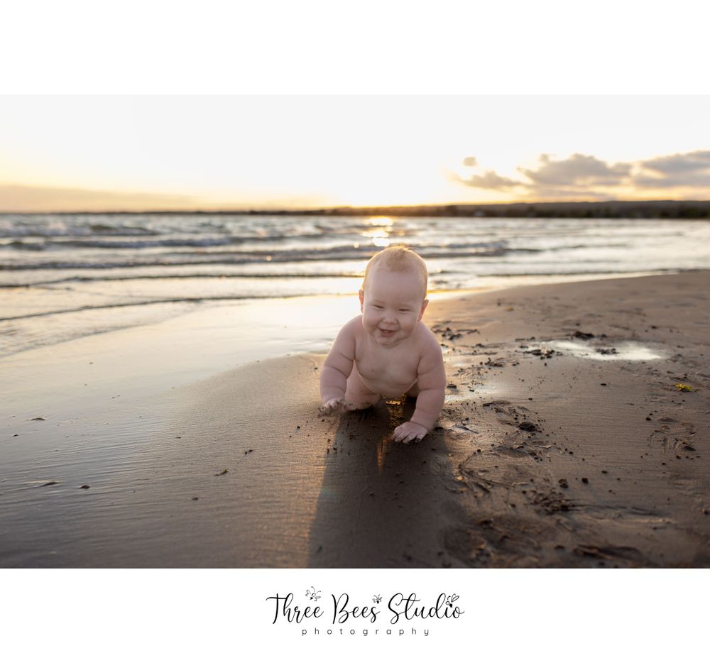 Young child playing on beach sand during golden hour sunset.
