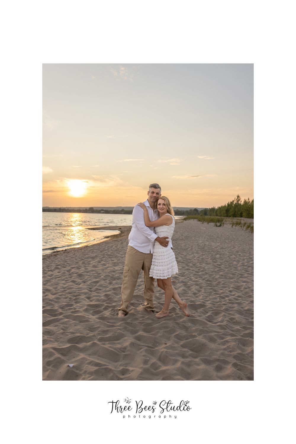 Romantic beach portrait of couple embracing at sunset on sandy shore.