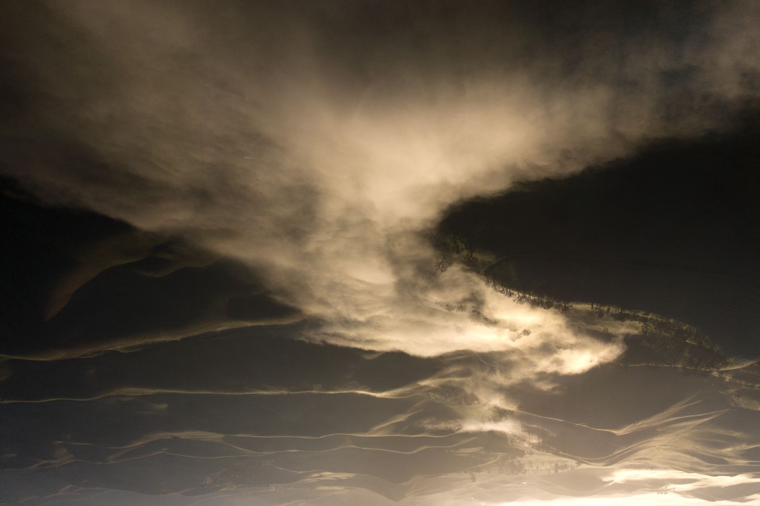 Dramatic wispy clouds streak across a dark moody sky with golden sunlight filtering through the formations.